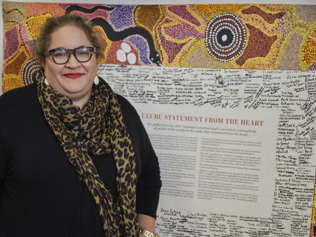 Professor Megan Davis in front of artwork displaying the Uluru Statement from the Heart