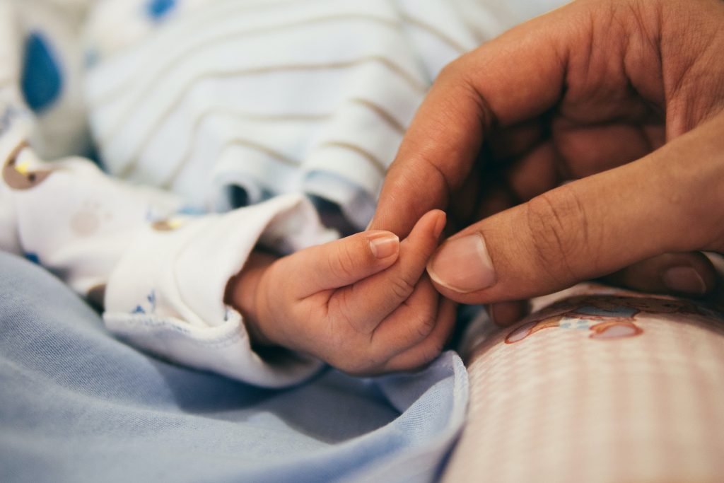 Newborn baby hand being held by an adult